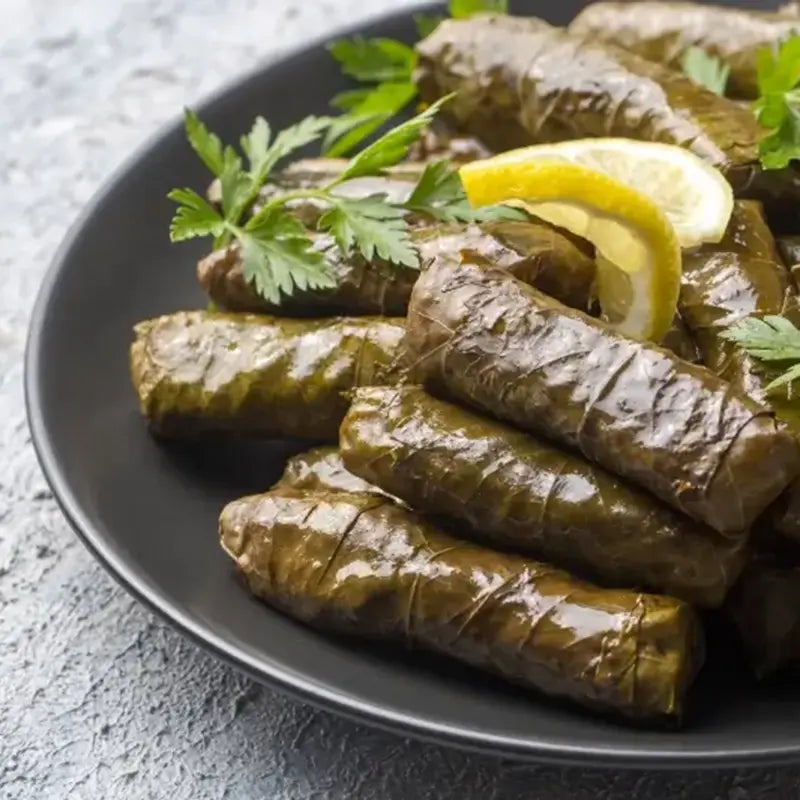 Gefüllte Weinblätter (Dolmades) von Antipasti-Versand, serviert mit Zitrone und Petersilie